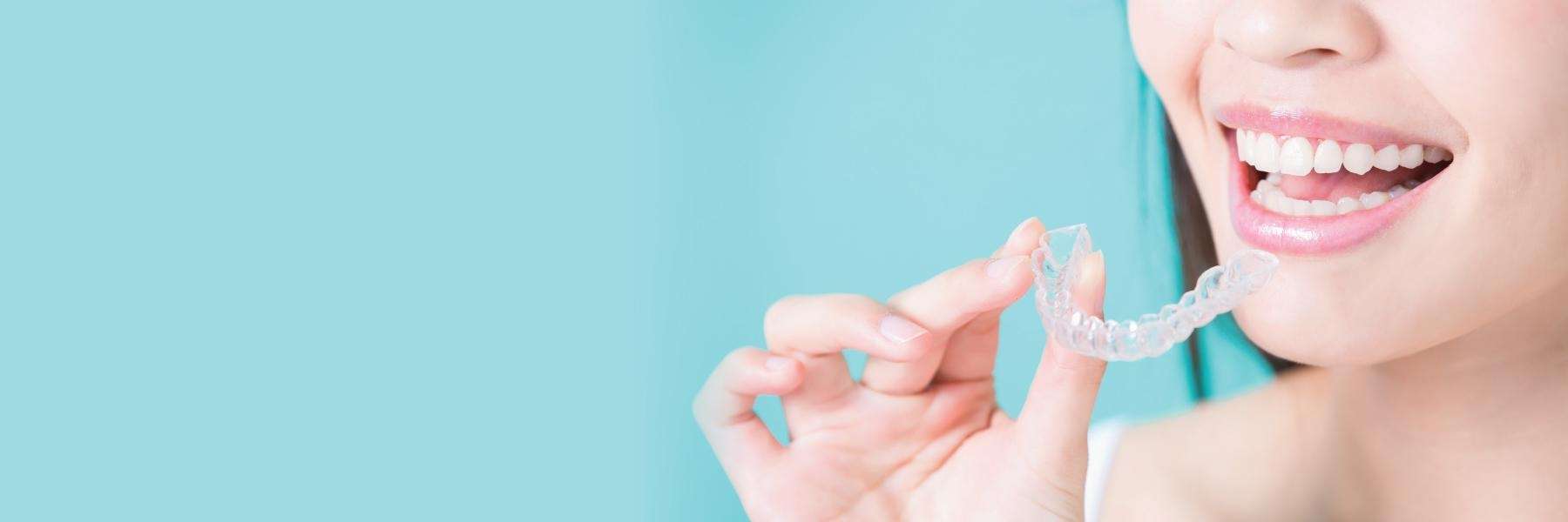 A woman holding an Invisalign tray