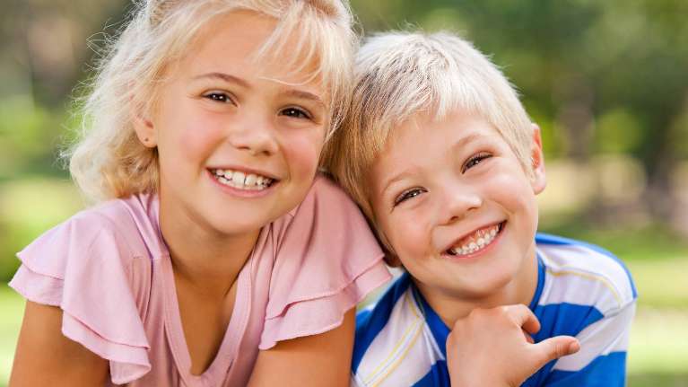 A brother and sister smiling outside